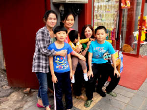 Pattie with shopkeeper's family in Beijing.JPG